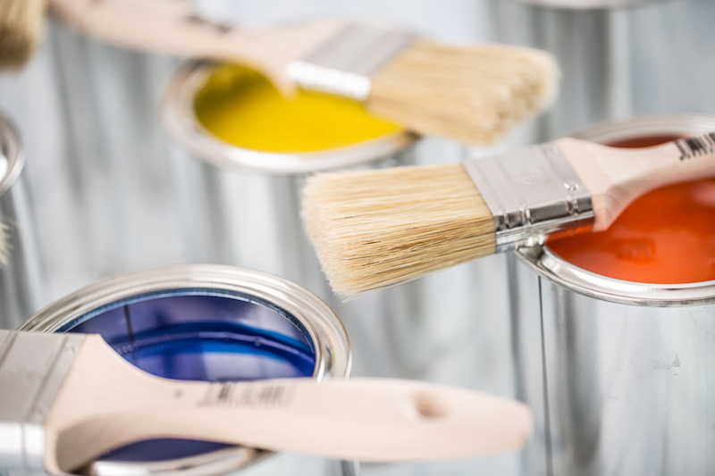 Close-up brushes lying on multicolored paint cans.